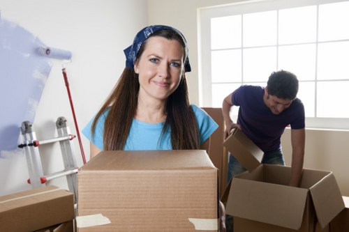Movers carrying boxes and furniture from a Roehampton flat with stairs